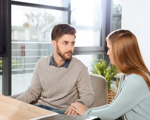 young couple looking at each other while sitting together at psychotherapy