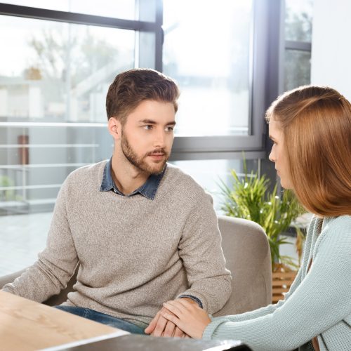 young couple looking at each other while sitting together at psychotherapy